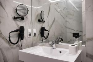 Baño blanco con lavabo y espejo en Hotel Europejski Wrocław Centrum en Wroclaw