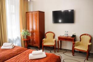 a hotel room with two beds and a desk and a television at Hotel Europejski Wrocław Centrum in Wrocław
