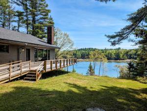 a house with a large deck next to a lake at Frenchman Bay Oceanfront Getaway in Sullivan