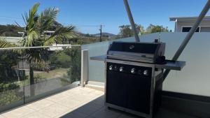 a grill on a balcony with a view of a house at Myall Views From Majestic #7 in Hawks Nest +11 photos