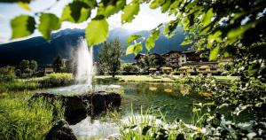 a fountain in the middle of a pond in a park at Forster's Naturresort in Neustift im Stubaital