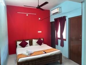 1 dormitorio con 1 cama con pared roja en Auro Galaxy Pondy with Swimming Pool en Kottakupam