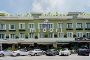 een groot gebouw met auto's geparkeerd op een parkeerplaats bij Midori Concept Hotel in Johor Bahru