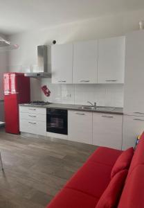 een keuken met witte kasten en een rode bank bij Mo&Ma Home in Imola