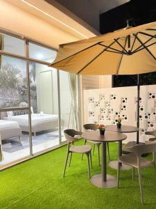 ウル・ティラムにあるHeliconia Design Home With Pool BBQ KTV JB AEON Tebrauのテーブル、椅子、傘のある部屋