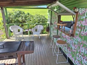 a covered deck with chairs and tables and a grill at Mountain View Tilba Tilba - Glamping in Tilba Tilba +28 photos