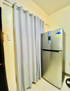einen Kühlschrank aus Edelstahl in einem Zimmer mit Vorhängen in der Unterkunft 3 Bedroom House near Davao Airport in Davao City