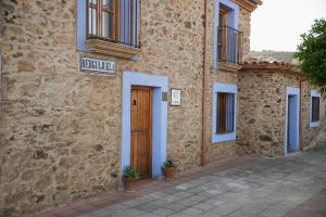 a stone building with a door and a sign on it at CASA RURAL La Moranta in Herguijuela