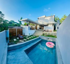 a house with a swimming pool with a pink boat in it at Orchids Villa Elnido in El Nido