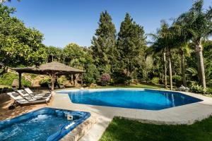 a swimming pool with two chairs and a gazebo at Villa Bermeja in Casares