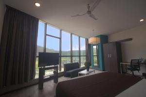 a bedroom with a bed and a television and a chair at Hotel Mumbai House Airoli, Navi Mumbai in Navi Mumbai