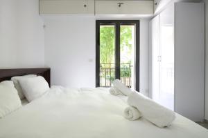 a white bedroom with a large white bed with towels on it at 2 BR next to Old City with Patio by FeelHome in Jerusalem