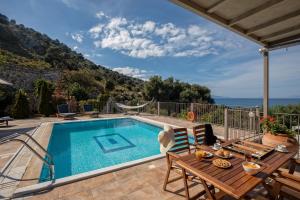 a villa with a swimming pool and a table and chairs at Dalasvillas SkalaAcqua in Skala