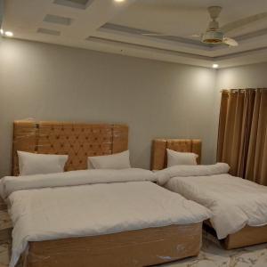 2 nebeneinander sitzende Betten in einem Schlafzimmer in der Unterkunft Hotel Crown Palace in Murree