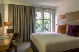 une chambre d'hôtel avec un lit et une fenêtre dans l'établissement Grand Hôtel Roi René Aix en Provence Centre - MGallery, à Aix-en-Provence