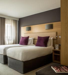 um quarto de hotel com duas camas com almofadas roxas em Grand Hôtel Roi René Aix en Provence Centre - MGallery em Aix-en-Provence