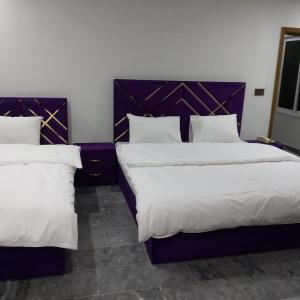 2 Betten in einem Hotelzimmer mit weißen Kissen in der Unterkunft Hotel Crown Palace in Murree