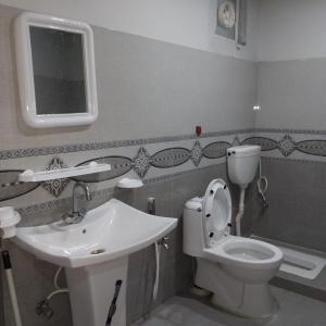 uma casa de banho com um WC branco e um lavatório. em Hotel Crown Palace em Murree