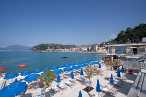 a group of blue umbrellas and chairs on a beach at Hotel San Terenzo in Lerici