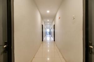 un pasillo largo con paredes blancas y suelo de baldosa blanca en OYO Flagship Our Palace en Gunadala