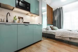 a bedroom with a bed and a blue kitchen at Stylowe Apartamenty w Centrum in Wrocław