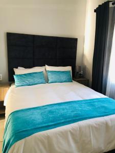 um quarto com uma cama grande e almofadas azuis em Elihle Guest house em Empangeni