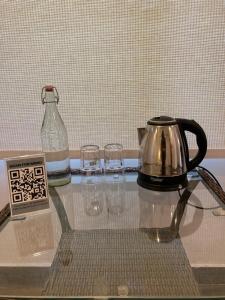 un tavolo in vetro con bollitore per tè e bicchieri sopra di Himtrek Stays,Mcleodganj a McLeod Ganj