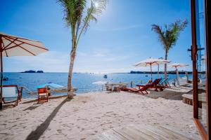 ein Strand mit Liegestühlen und Sonnenschirmen und das Meer in der Unterkunft BE Villa - Phu Quy Island in Cu Lao Thu