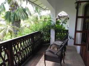 a balcony with two chairs and plants on it at Langi Langi Beach Bungalows in Nungwi