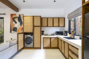 cocina con armarios de madera, lavadora y secadora en Sicilia Villa by DH Ubud, en Ubud
