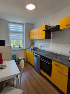 eine Küche mit gelben Schränken und einem Tisch in der Unterkunft Andrews Ferienwohnungen in Tangermünde
