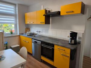 a kitchen with yellow cabinets and a stove at Andrews Ferienwohnungen in Tangermünde