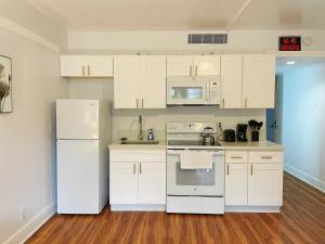 a kitchen with white appliances and white cabinets at Studio in Hilo Center with Pool and Lake Views in Hilo