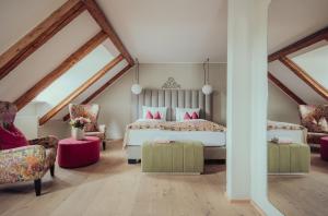 a attic bedroom with a bed and two chairs at Romantik Spa Hotel Elixhauser Wirt in Elixhausen