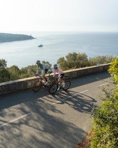 dwoje ludzi jeżdżących rowerami po drodze blisko oceanu w obiekcie Penthouse over Monaco w mieście Beausoleil