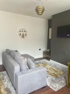 Clifton Home - Newly refurbished - Perfect for contractors! في Killingbeck: غرفة معيشة مع أريكة وتلفزيون بشاشة مسطحة