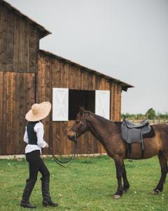 Una mujer paseando un caballo delante de un granero en Chateau Vartsikhe, en Varts'ikhe