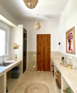 eine Küche mit einem Waschbecken und einer Holztür in der Unterkunft Lions Grand SUITE Ocean Front Beach & Pool in Bunju