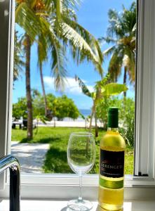 eine Flasche Wein neben einem Weinglas in der Unterkunft Lions Grand SUITE Ocean Front Beach & Pool in Bunju