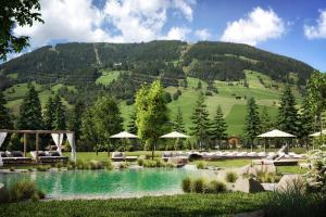 um resort com uma piscina com uma montanha ao fundo em Traumhotel Alpina Superior Adults Only Hotel em Gerlos