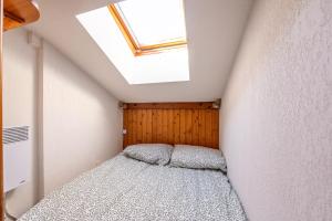 a small attic bedroom with a bed and a skylight at Les Belles d'Arly - Appt vue montagne in Praz-sur-Arly