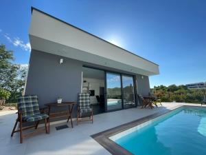a house with a swimming pool and two chairs and a table at Villa Narona in Medulin