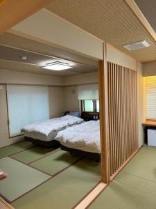 1 dormitorio con 2 camas y un espejo grande en Oshi Ryokan en Nagano