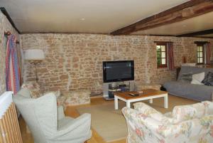 a living room with a couch and a tv at Les Roses, avec piscine, tennis et lac privatif in Guerquesalles