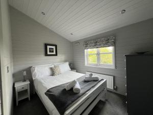 Un pequeño dormitorio con una cama con toallas. en Holly Blue - Cosy wooden lodge Kippford en Dalbeattie