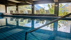 keyone rooms Montafon في شرونس: مسبح مع كراسي وإطلالة على الجبال