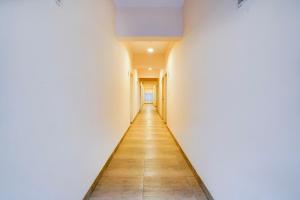un long couloir avec des murs blancs et du parquet. dans l'établissement FabHotel GRK Comforts, à Bangalore