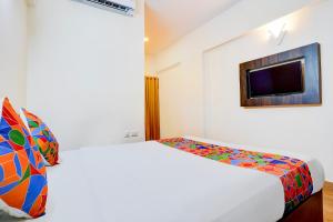una camera bianca con letto e TV di FabHotel GRK Comforts a Bangalore