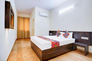 班加罗尔FabHotel GRK Comforts - Jayanagar的卧室里有一张带木质床头板的大床