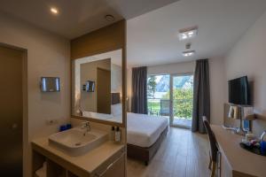 a hotel room with a bed and a sink and a mirror at Hotel Bellariva in Riva del Garda